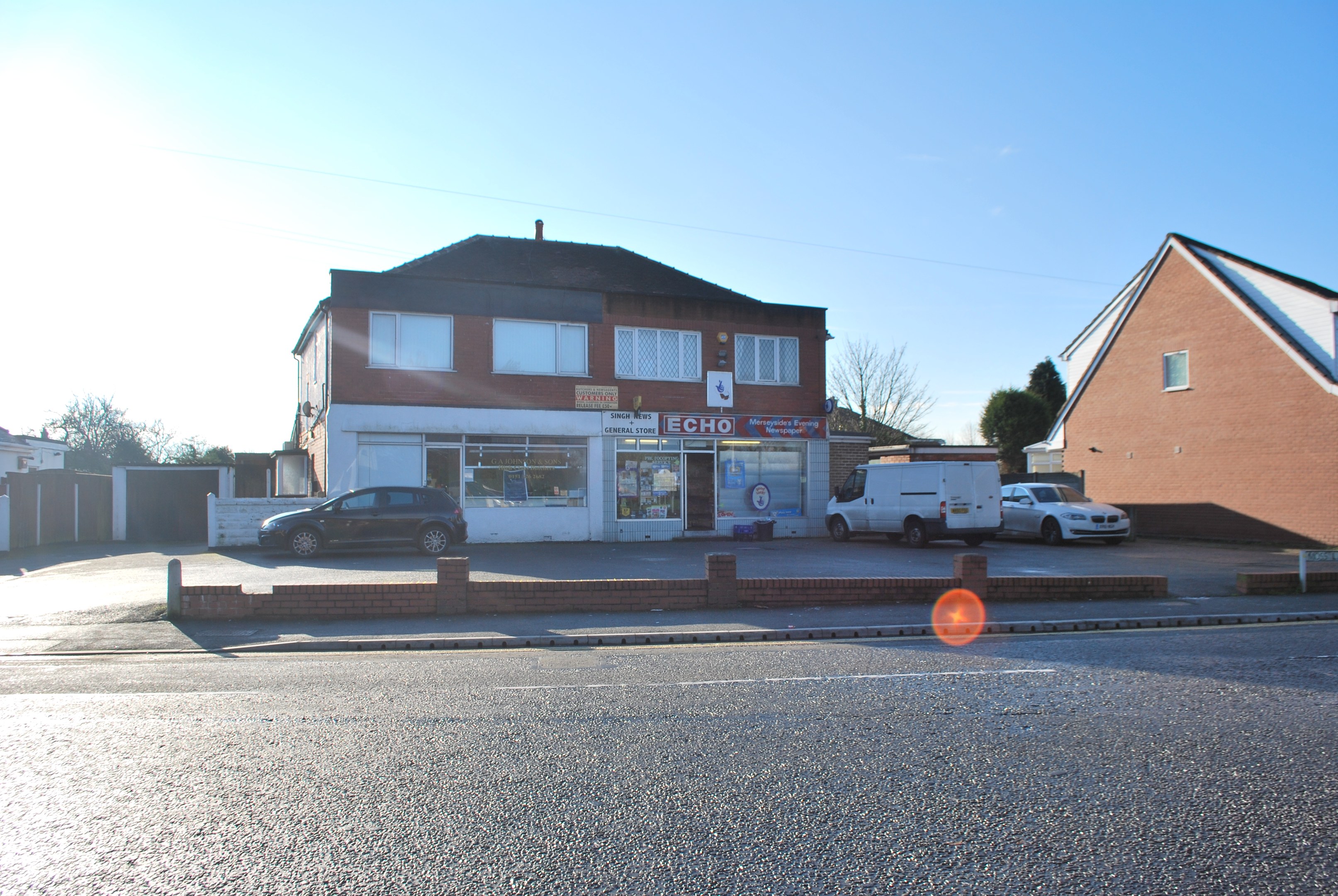 Gewerbliches Objekt zum Verkauf an der St Johns Road, Luton, Bedfordshire, mit Gebäuden, Fahrzeugen, einer Wand, Bäumen und einem wolkenverhangenen Himmel.