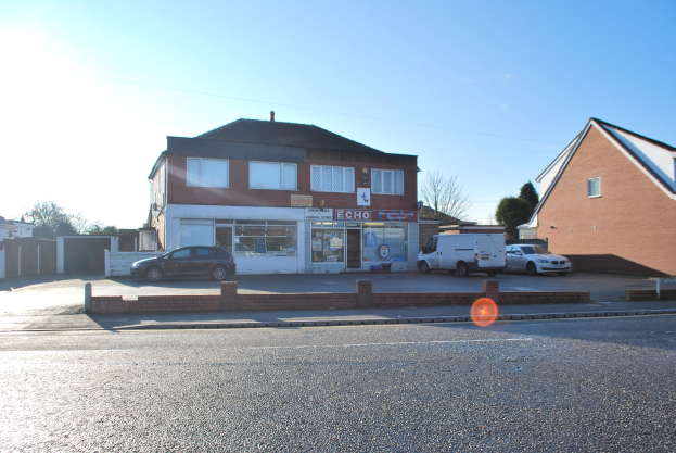 Gewerbliches Objekt zum Verkauf an der St Johns Road, Luton, Bedfordshire, mit Gebäuden, Fahrzeugen, einer Wand, Bäumen und einem wolkenverhangenen Himmel.