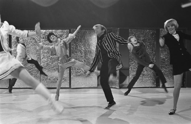 Schwarzes und weißes Bild von Menschen, die auf einer Bühne tanzen, mit einer Wand im Hintergrund und allen Schuhen.
