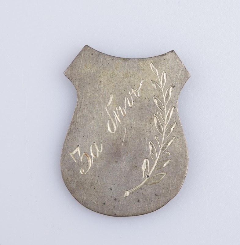 Ein silbernes Abzeichen mit einem Lorbeerkranz, darauf die Inschrift "50. Hochzeitstag", auf einem weißen Hintergrund.