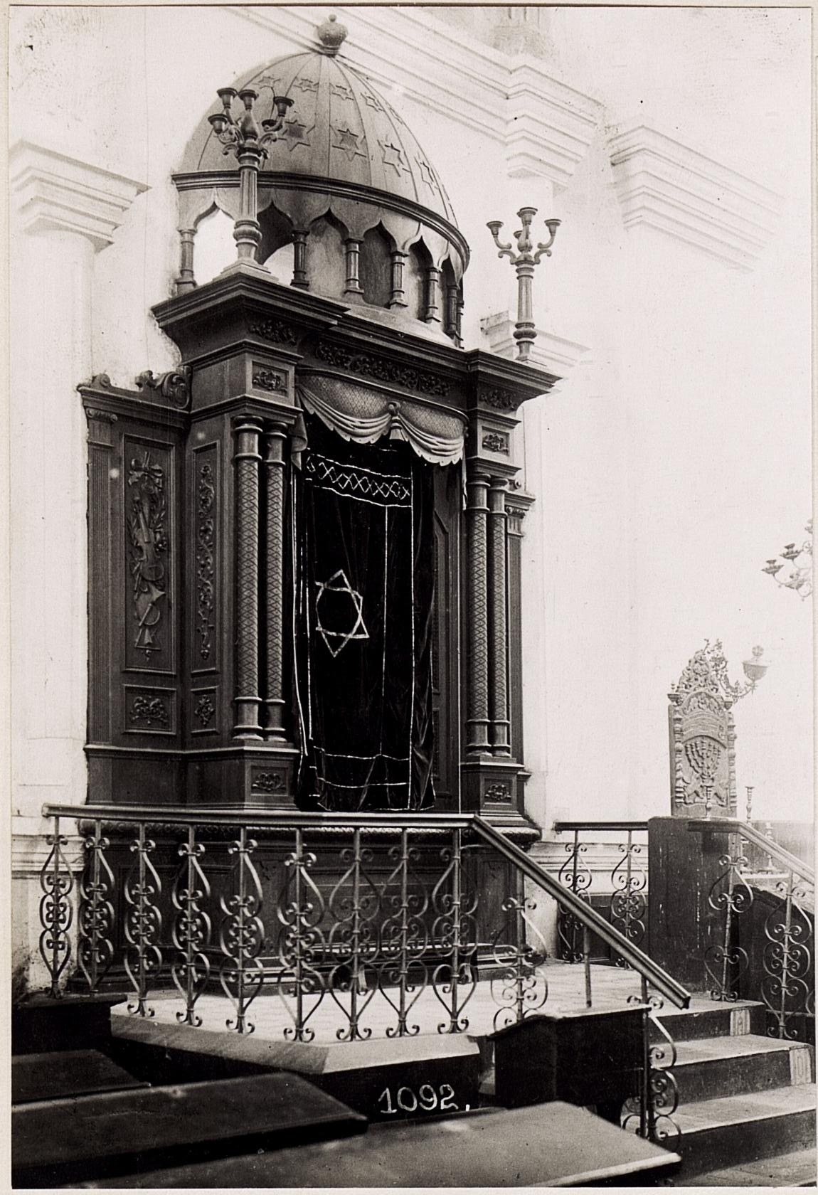Schwarzes und weißes Foto einer jüdischen Synagoge in New York City, das Treppen, Geländer, Säulen, eine Tür und eine Wand zeigt.