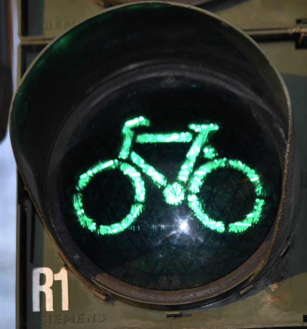 Grüne Ampel mit Fahrradsymbol, das an einer Wand leuchtet.