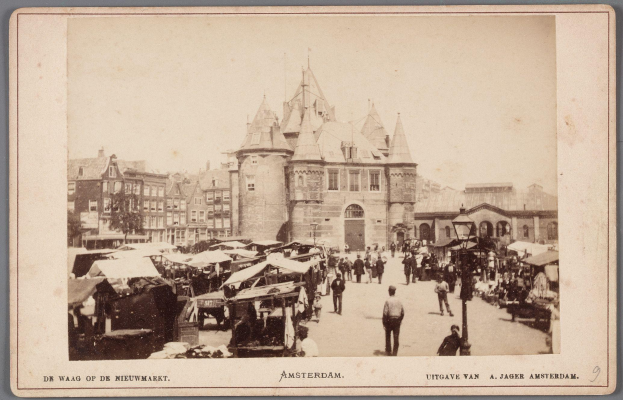 Schwarz-weiß-Foto eines belebten Marktes in Amsterdam mit Menschen, Ständen und Gebäuden im Hintergrund, mit Text unten.