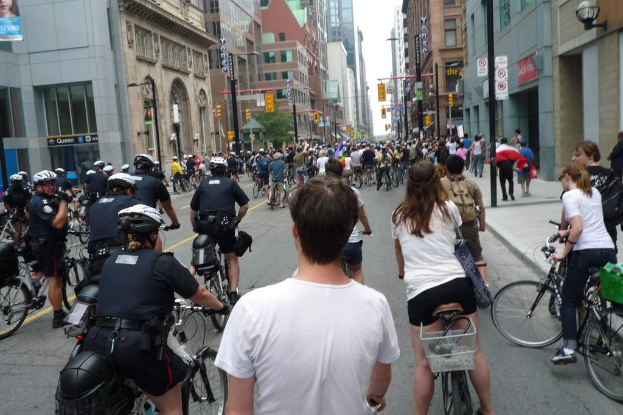 Geb\303\244ude und mehrere Menschen auf Fahrr\303\244dern auf einer Stra\303\266.