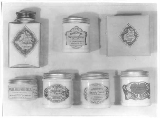 Schwarzes und weißes Foto eines Regals mit ordentlich angeordneten Sahnetöpfchen, die alle mit verschiedenen Arten beschriftet sind.