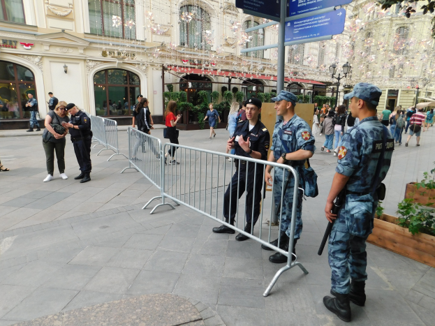 Polizeibeamte in Uniform stehen hinter Barrikaden und blicken auf eine Menge, von der einige Kappen tragen und Waffen halten, mit Schildern und Gebäuden im Hintergrund in Wien während einer Anti-Terror-Operation.