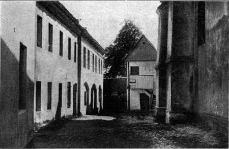 Schwarz-weiß-Foto eines alten Gebäudes mit der Beschriftung "Grundfosz, das ehemalige Gefängnis in der Stadt Stuttgart, Deutschland" mit Fenstern, einem Baum und Himmel im Hintergrund.