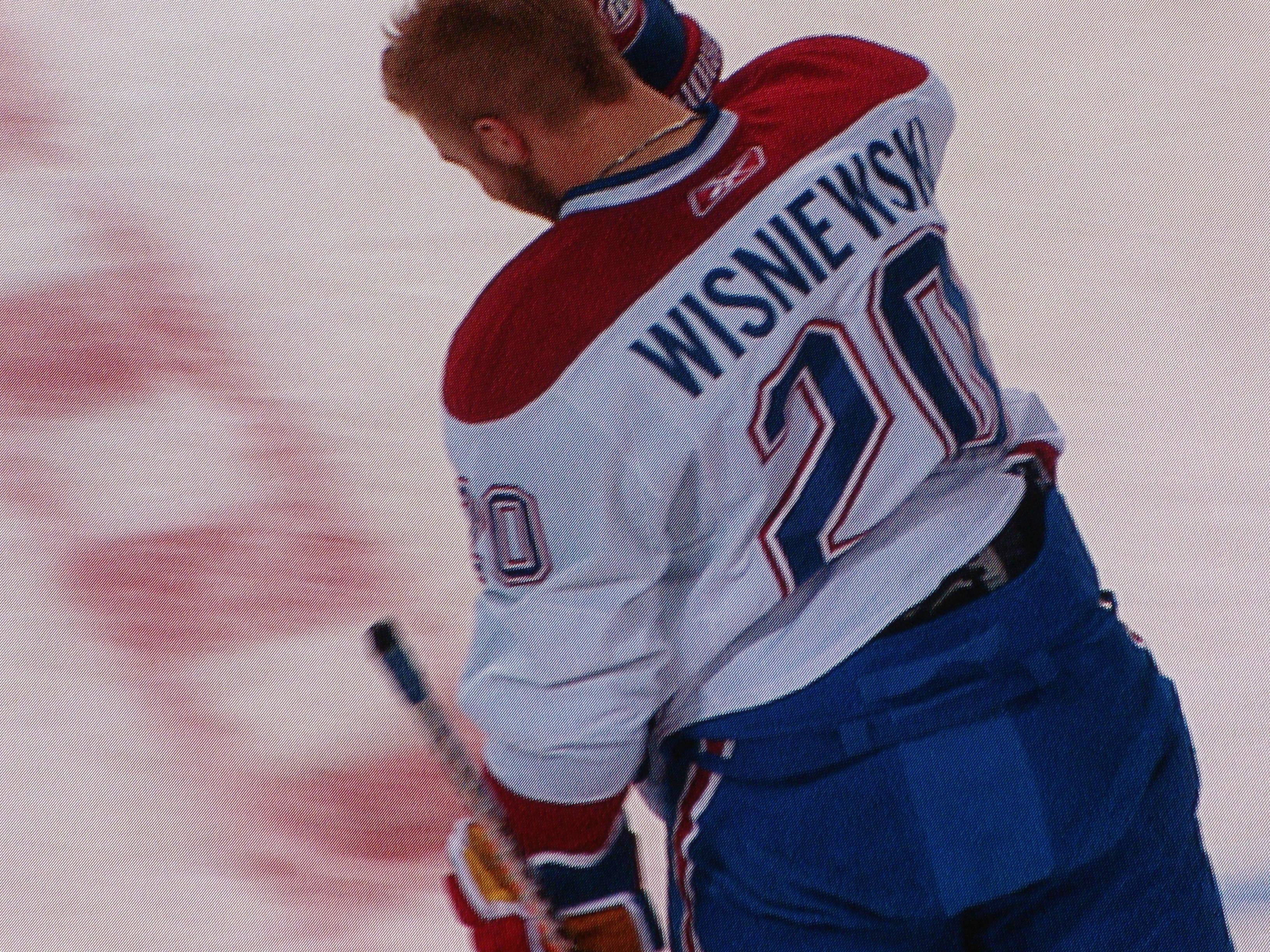 Ein Hockey-Spieler im 'Wisniewski'-Trikot steht auf dem Eis und hält einen Hockey-Schläger in der Hand.