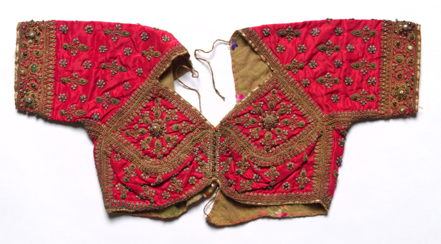 Rotes Oberteil mit goldener Stickerei, das aufwändige Designs zeigt, vor einem weißen Hintergrund.