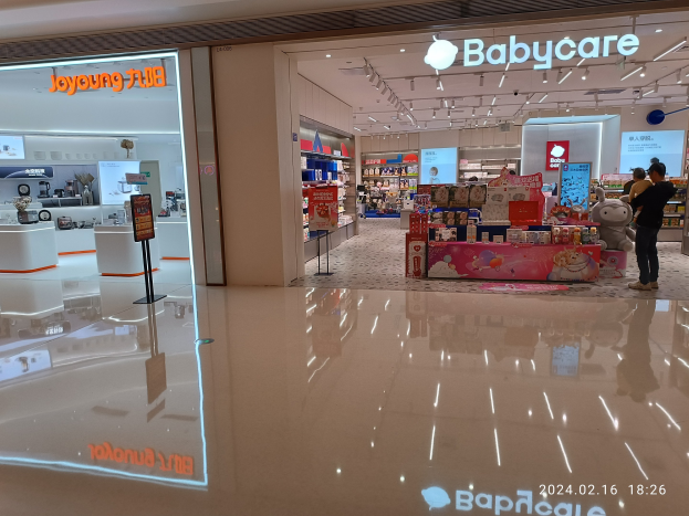 Ein Babypflegegeschäft in einem Einkaufszentrum mit Menschen, Spielzeugen, Regalen, Schildern, einem Bildschirm und Deckenleuchten, das sich im Mall of Asia befindet.
