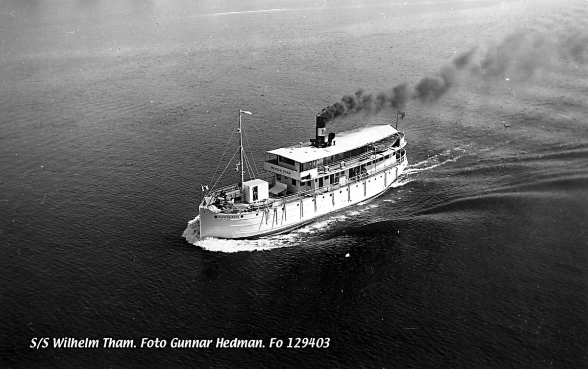 Schwarz-weißes Foto eines Boots mit Rauch, das auf dem Wasser fährt, mit Text unten.