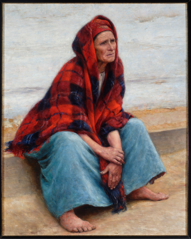 Eine alte Frau sitzt bei Sonnenuntergang auf einem Strand, trägt ein helles Kleid mit einem Dutt, hat die Augen geschlossen und die Hände auf dem Schoß, eingerahmt von einem Foto Rahmen.