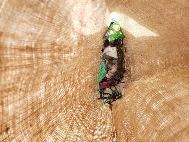 Nahaufnahme eines Stücks Papiermüll auf einem Tisch mit einem Jutestoff-Hintergrund.