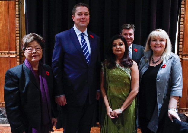 Gruppe von Menschen vor einem schwarzen Vorhang mit einer hölzernen Wand im Hintergrund, die scheinbar Mitglieder der FDP auf einer Versammlung sind.