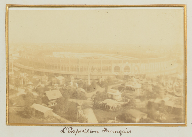 Altes Schwarz-Weiß-Foto eines Stadions umgeben von Gebäuden, Bäumen und Strommasten mit Text am unteren Rand.
