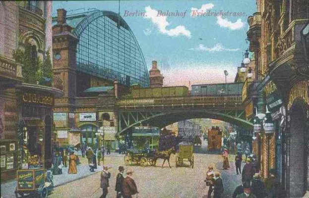 Alte Postkarte einer belebten Berliner Straße mit Fußgängern, Pferdewagen, Gebäuden, einer Brücke und bewölktem Himmel, mit Text oben.