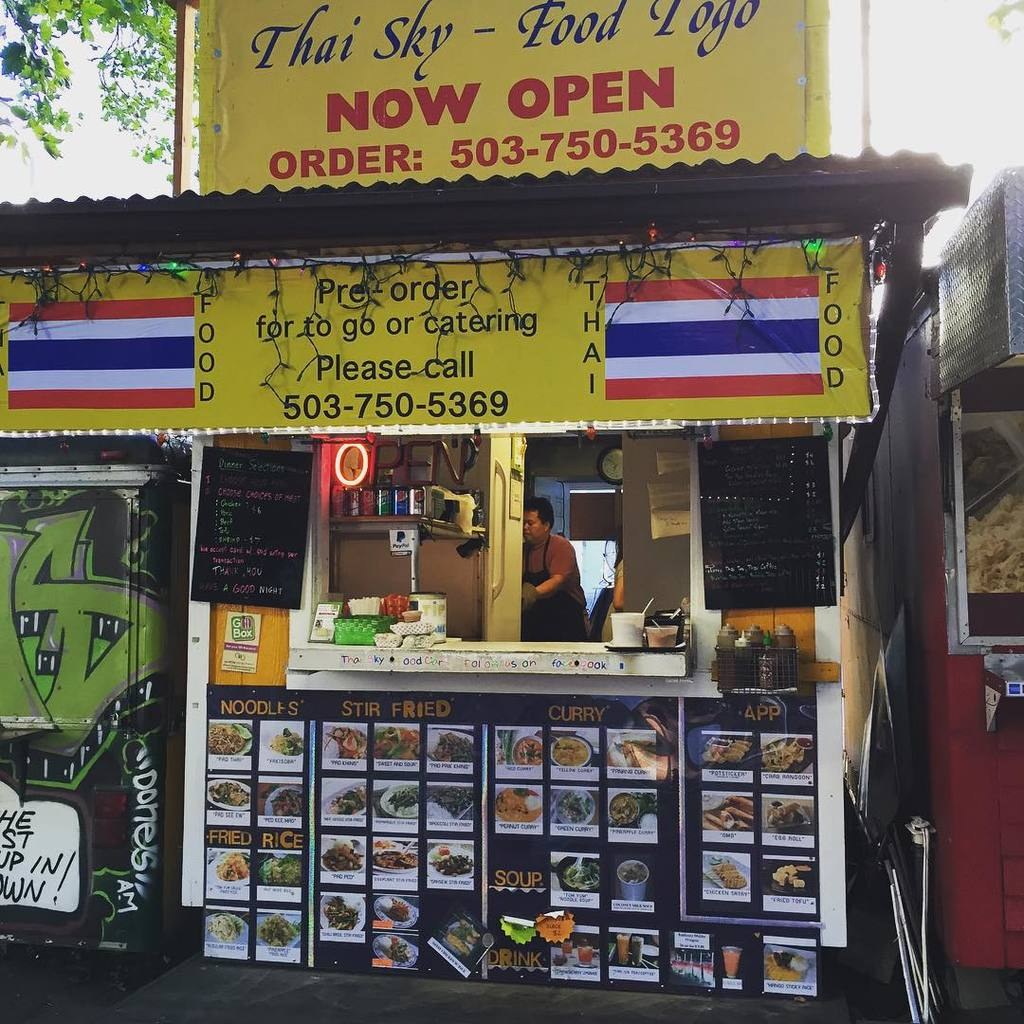 Ein Geschäft mit verschiedenen Früchten und Gemüsen in Kartons mit Preisschildern, Informationsschilder an den Wänden und Deckenbeleuchtung.