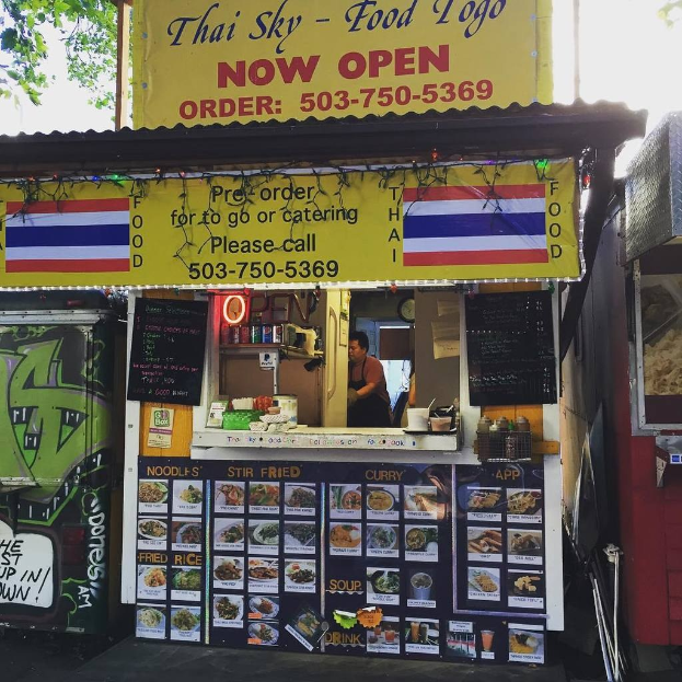 Ein Geschäft mit verschiedenen Früchten und Gemüsen in Kartons mit Preisschildern, Informationsschilder an den Wänden und Deckenbeleuchtung.