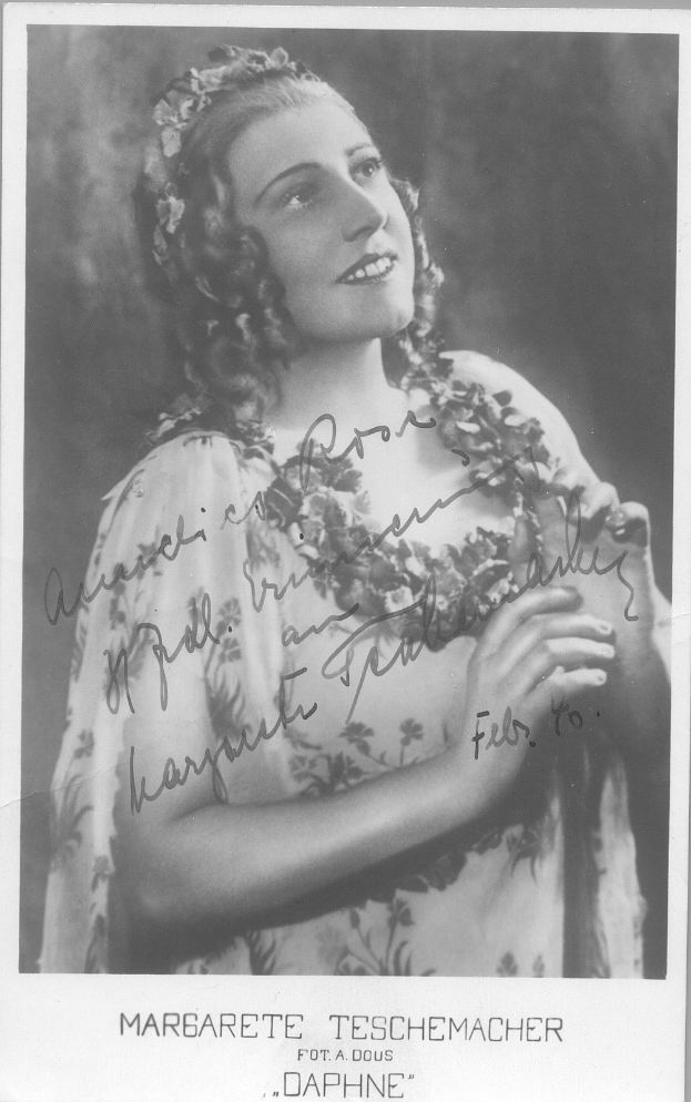 Ein Schwarz-Weiß-Foto einer Frau in einem Kleid mit einer 1940er-Jahre-Frisur, die warm lächelt mit hellen Augen und leicht geöffneten Lippen.