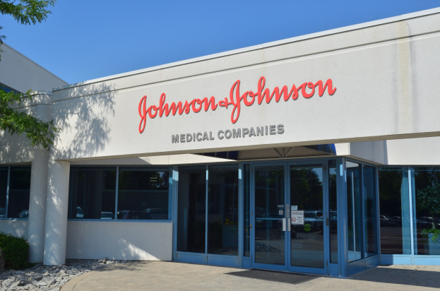 Das Johnson & Johnson Medical Companies-Gebäude mit Glaswänden und -türen, Text an der Wand, Steinen, Pflanzen und einem Baum auf der linken Seite, vor einem klaren blauen Himmel.