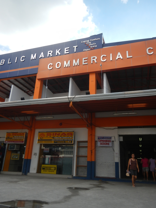 Ein öffentliches Marktgebäude mit Menschen davor, mit Text auf dem Gebäude und einem sichtbaren Himmel oben.