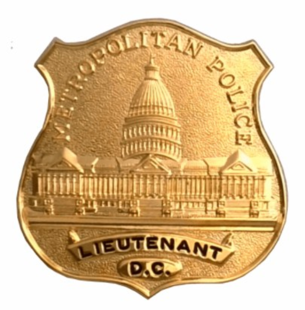 Goldenes Polizeimarke mit "Leutnant DC" eingraviert auf weißem Hintergrund.