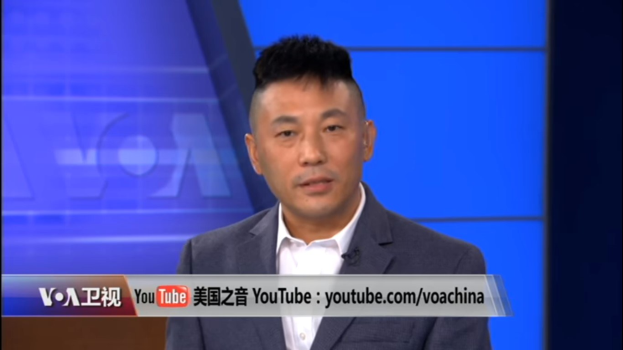 Ein Mann im Anzug und mit Krawatte auf einem Fernseher mit blauem Hintergrund, identifiziert als chinesischer Nachrichtensprecher durch den Text am unteren Bildrand.