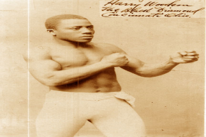 Ein Mann in einem Boxring, der Handschuhe und Shorts trägt und entschlossen aussieht, steht aufrecht und konzentriert.