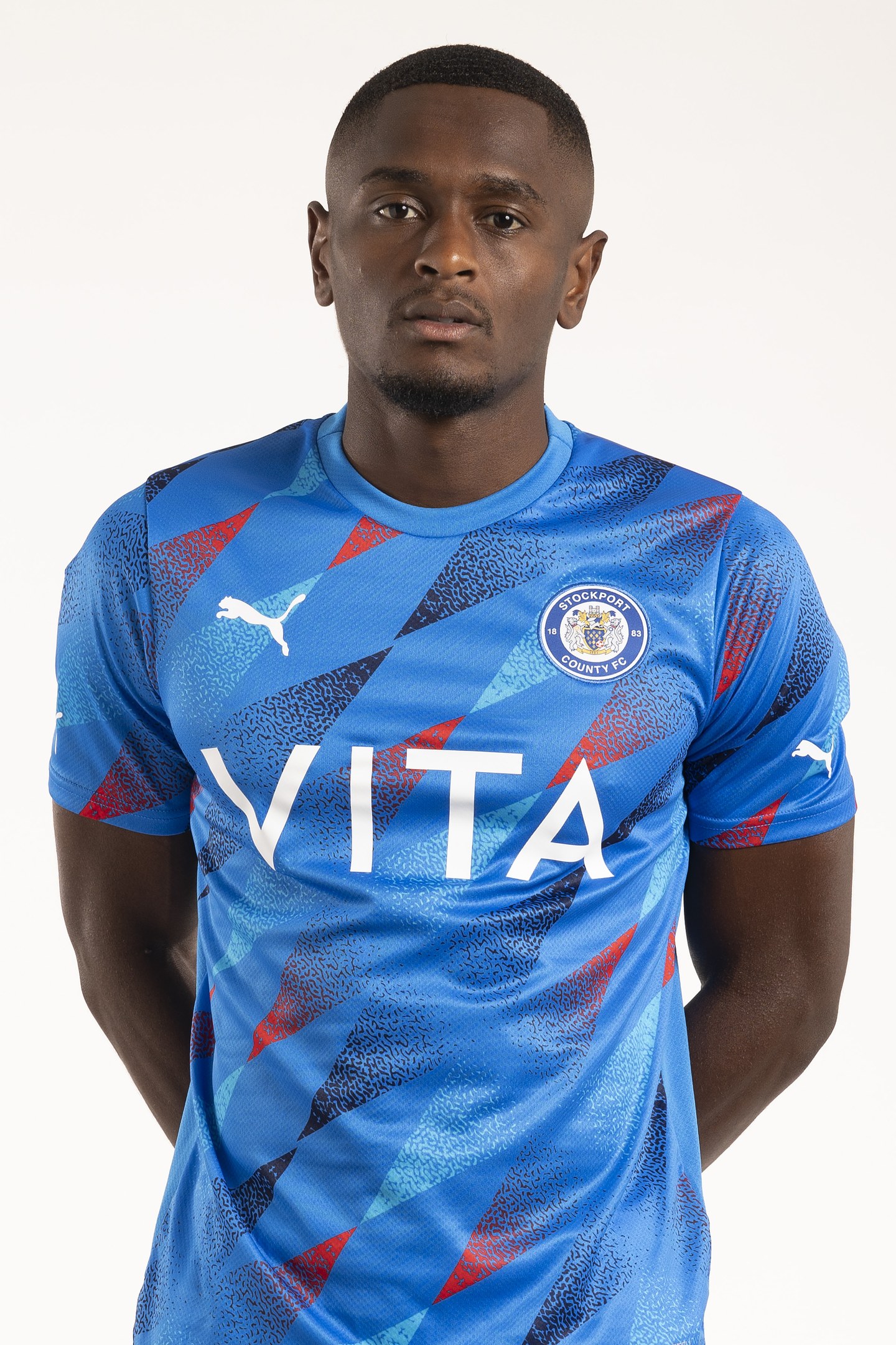 Ein Mann in einem blauen Leicester City Away-Shirt von der Saison 2018-19, der mit Händen in den Taschen und einem leichten Lächeln steht.