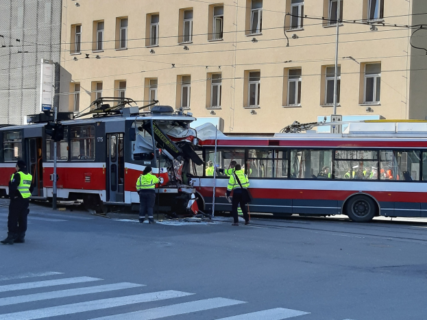 Rote und weiße Straßenbahn krachte auf die Straße mit ein paar Menschen in der Nähe und einem Gebäude im Hintergrund.
