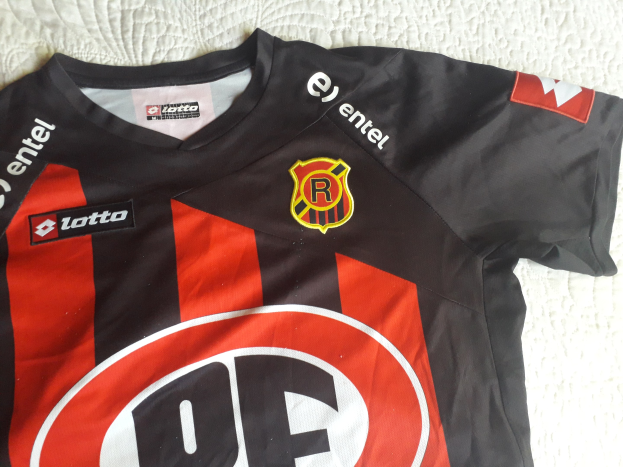 Schwarze und rote Fußballtrikots mit einer roten und schwarzen Streifen, mit einem Logo und Text auf einer weißen Oberfläche.
