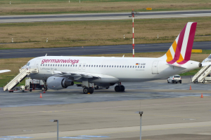 Germanwings Airbus A320-200 geparkt am Frankfurter Flughafen mit Bodenfahrzeugen, Verkehrskegeln, Versorgungsmasten und Gras im Hintergrund.