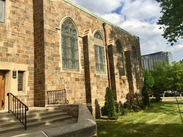Große steinerne Kirche mit grüner Dachterrasse, Treppe, Pflanzen, Bäumen, Fahrzeugen, benachbarten Gebäuden und bewölktem Himmel, beschriftet als St. Mary's Episcopal Church nach Renovierungen.
