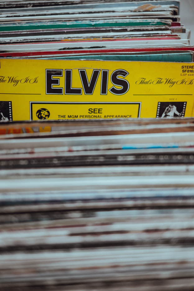 Ein ordentlicher Stapel Elvis-Presley-Platten auf einem Tisch, mit einigen überlappenden, lesbaren Titeln und einem unscharfen Hintergrund.